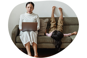 child playfully lying down while mother is on her laptop