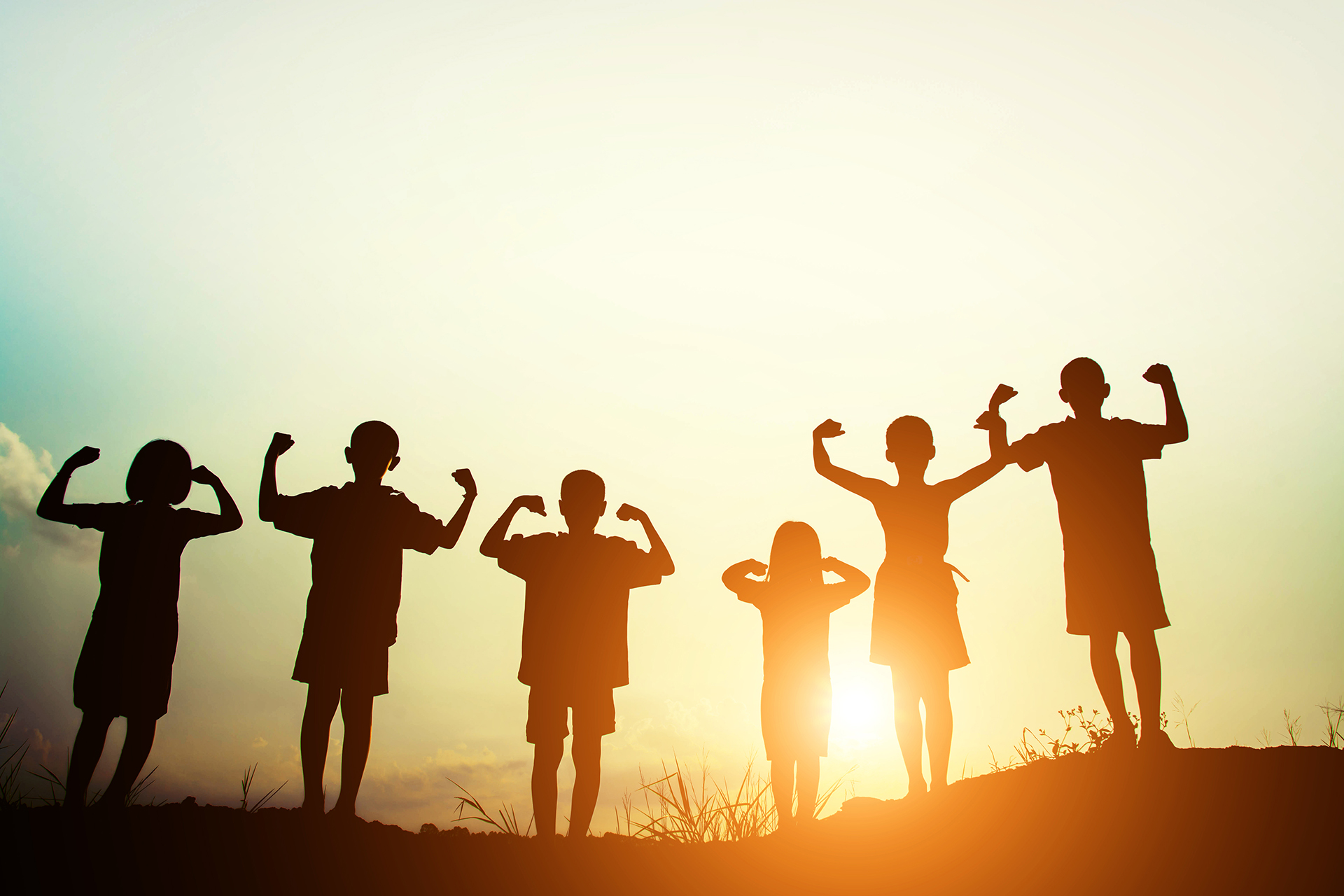 Silhouettes of a group of kids standing and showing their strength  