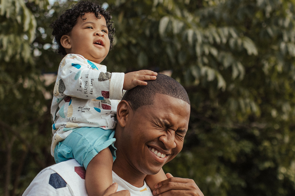 Man smiling with child on his shoulders